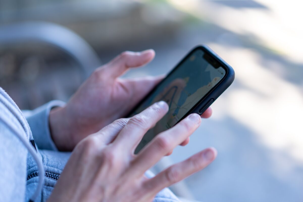 lady looking up navigation on phone while waiting 2022 11 16 14 06 05 utc 1200x800 - GPS Tracker Pferd Offenstall - für Reiter zum Ausreiten